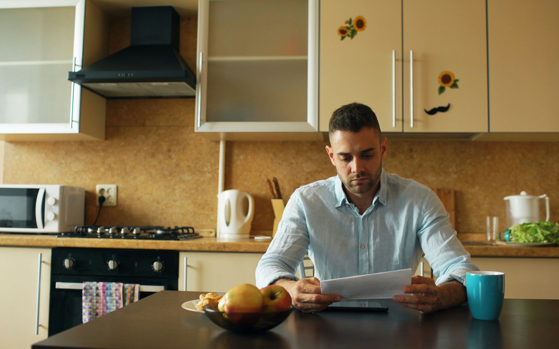 Een man leest aan de keukentafel een brief