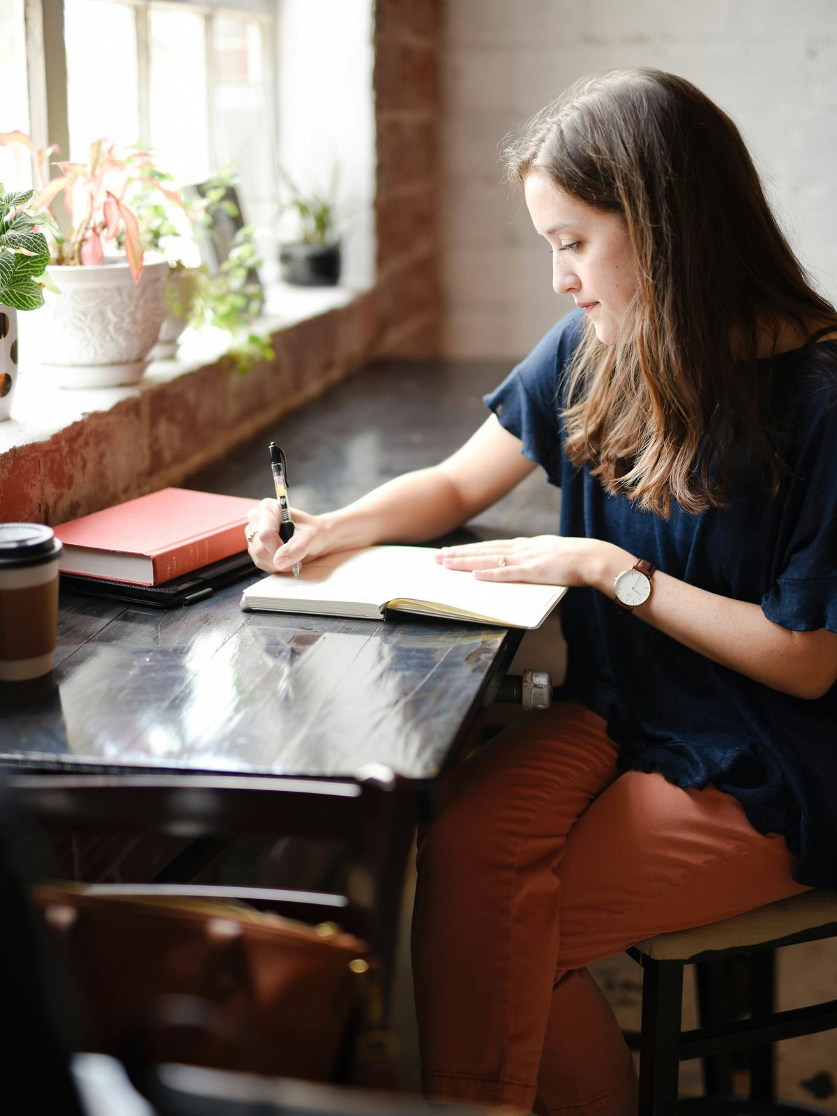 Een vrouw schrijft bij het raam in een notitieboek